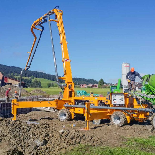Bomba de hormigón Atabey Scorpion vertiendo hormigón en una fundación encofrada, con un operario sobre la plataforma de control